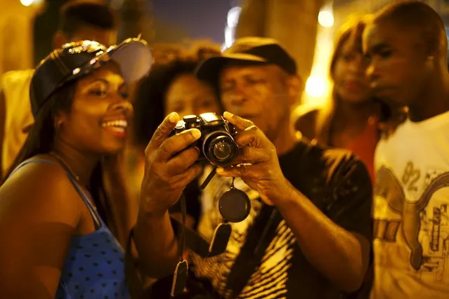 People look at pictures from a digital camera at Havana city, Cuba, March 17, 2016. (Photo by Ivan Alvarado/Reuters)