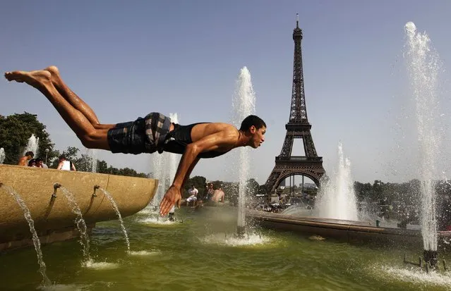 A young man jumps in a fountain of the Trocadero to cool off, in front of the Eiffel tower in Paris, August 19, 2012 as an unusual heatwave continues to hit continental Europe. (Photo by Vincent Kessler/Reuters)