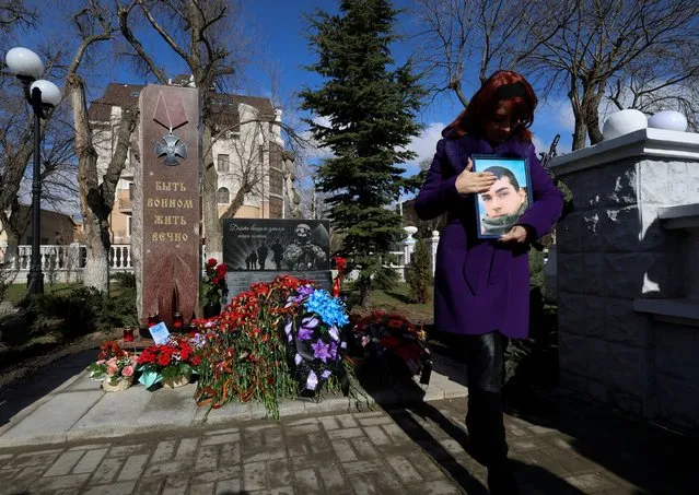 Natalia Patrashku holds a portrait of her son during the opening of the memorial to Russian service members killed during Russia-Ukraine conflict, in Yevpatoriya, Crimea on February 22, 2024. (Photo by Alexey Pavlishak/Reuters)