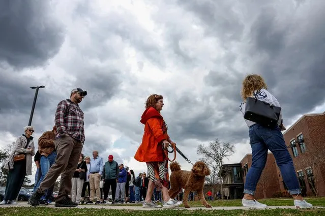 A woman with a dog stands in line to cast her vote in the South Carolina Republican presidential primary election, at the Jennie Moore Elementary School, in Mount Pleasant, South Carolina, U.S., February 24, 2024. (Photo by Evelyn Hockstein/Reuters)