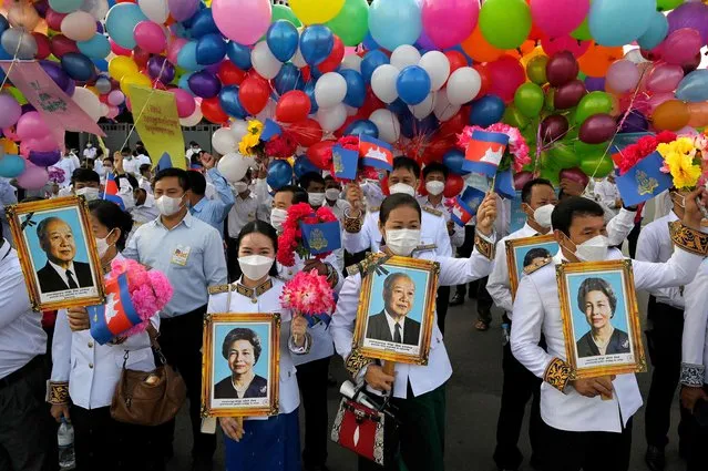 People hold portraits photos of former king Norodom Sihanouk and former queen Monique at the Independence Monument during a ceremony marking Cambodia's Independence Day in Phnom Penh on November 9, 2021. (Photo by Tang Chhin Sothy/AFP Photo)