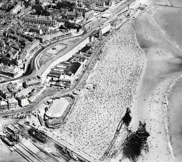 The Times weather forecast for 12 August 1947 advised that a ridge of high pressure had moved in over the British Isles, and that it will be fair and fine or warm. Just like the thousands of holidaymakers shown here spread out across nearly every grain of the Ramsgate Sands, Aerofilms were keen followers of the weather. Clear skies and bright sunlight provided optimal conditions for aerial photography and, particularly in the summer months, almost guaranteed that a flight to the coast would offer up iconic, postcard-friendly shots of the British seaside experience. 1947. (Photo by Aerofilms Collection via “A History of Britain From Above”)
