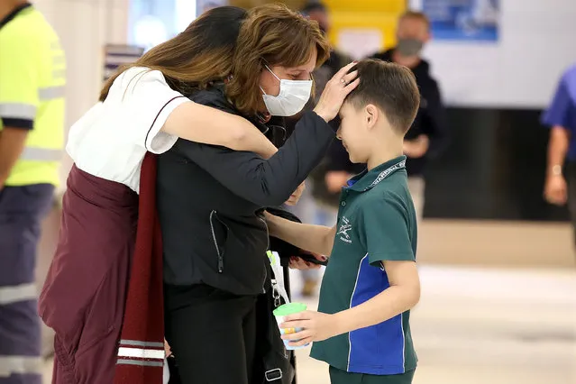 A mother is reunited with her children after 8 months, as travellers from Sydney arrive at Brisbane Airport in Brisbane, Tuesday, November 16, 2021. Home quarantine is being offered to domestic arrivals from COVID-19 hotspots now that more than 70 per cent of Queenslanders are fully vaccinated. (Photo by Jono Searle/AAP Image)