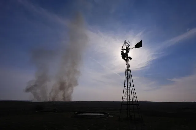 Smoke billows on a field near a windmill during the Smokehouse Creek Fire, Wednesday, February 28, 2024, in Canadian, Texas. (Photo by Julio Cortez/AP Photo)