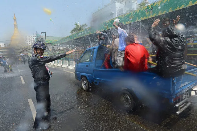 A policeman directs traffic as Myanmar revellers and tourists take part in wet celebration marking Thingyan, a water festival which brings in the countrys new year, in Yangon on April 12, 2016. The Buddhist festival of water pouring symbolizes spiritual cleansing and begin the new year free from worldly impurities with celebrants devoting the four days of Thingyan in merry making of water dousing until the eve of new year. (Photo by Romeo Gacad/AFP Photo)