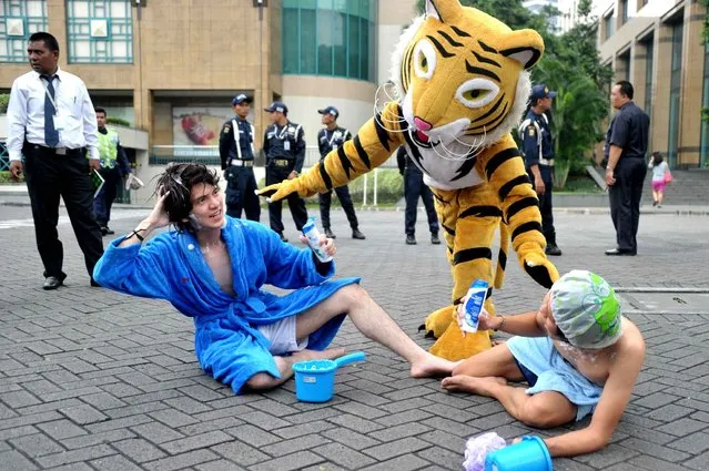Greenpeace activists dramatise a protest against US consumer goods giant Procter & Gamble outside a building housing the P&G office in Jakarta on March 26, 2014. Environmental group Greenpeace accused US consumer goods giant Procter & Gamble of responsibility for the destruction of Indonesian rainforests and the habitat of endangered orangutans and tigers. (Photo by Bay Ismoyo/AFP Photo)