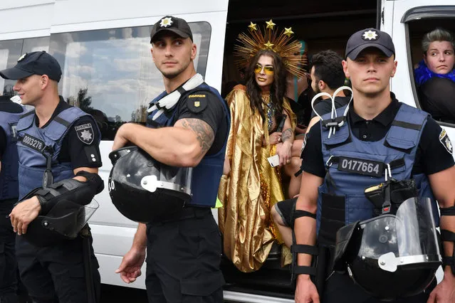 A participant looks around while sitting in a bus as policemen stand guard during the annual Gay Pride parade in Kiev on June 23, 2019. (Photo by Genya Savilov/AFP Photo)