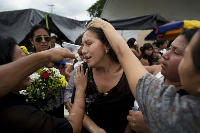 A mourner is revived with spalashes of water, before family members head to a nearby cemetery to bury their loved ones who were victims of the 7.8-magnitude earthquake, in Portoviejo, Ecuador, Monday, April 18, 2016. (Photo by Rodrigo Abd/AP Photo)