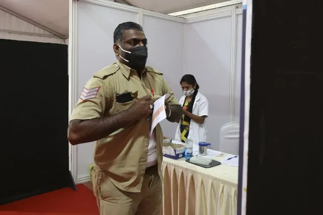 An Indian policeman buttons up his shirt after receiving the third dose of COVID-19 vaccine at a vaccination center in Bengaluru, India, Monday, January 10, 2022. Healthcare and front-line workers along with people above age 60 with health problems lined up Monday at vaccination centers across India to receive a third vaccination as infections linked to the omicron variant surge. India calls these “precautionary” doses and not boosters. (Photo by Aijaz Rahi/AP Photo)