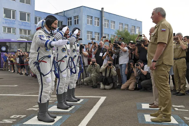 From left: U.S. astronaut Andrew Morgan, Russian cosmonaut Alexander Skvortsov and Italian astronaut Luca Parmitano, members of the main crew of the expedition to the International Space Station (ISS), report to head or Russian space agency Dmitry Rogozin prior the launch of Soyuz MS-13 space ship at the Russian leased Baikonur cosmodrome, Kazakhstan, Saturday, July 20, 2019. (Photo by Kirill Kudryavtsev/AP Photo/Pool)