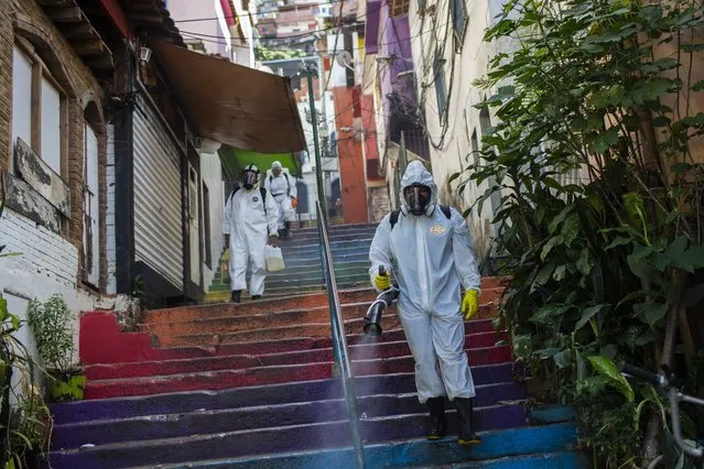 Thiago Firmino, right, sprays disinfectant to help contain the spread of the new coronavirus, in the Santa Marta slum of Rio de Janeiro, Brazil, Saturday, April 24, 2021. (Photo by Bruna Prado/AP Photo)