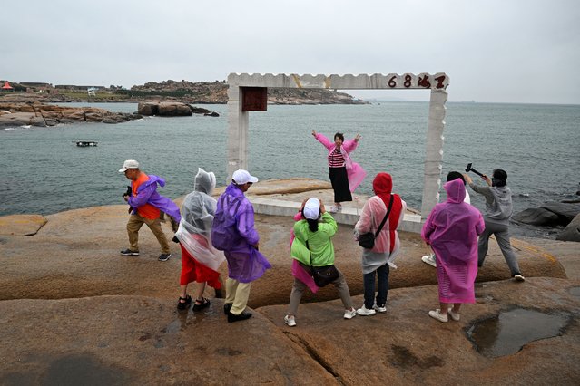 A woman poses for a photo while visiting a scenic spot called 68 Nautical Miles on Pingtan island, the closest point in China to Taiwan's main island, in Fujian province on May 20, 2024. (Photo by Hector Retamal/AFP Photo)