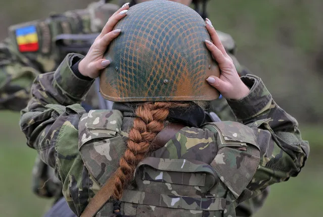 A Romanian female soldier adjusts her helmet before taking part in weapons training with US Marines female counterparts at the Capu Midia Surface to Air Firing Range, on the Black Sea coast in Romania, Monday, March 20, 2017. About 1,200 US and Romanian troops take part in the Spring Storm 17 exercise, meant to simulate defense of the Romanian Black Sea coastline and urban areas. (Photo by Vadim Ghirda/AP Photo)