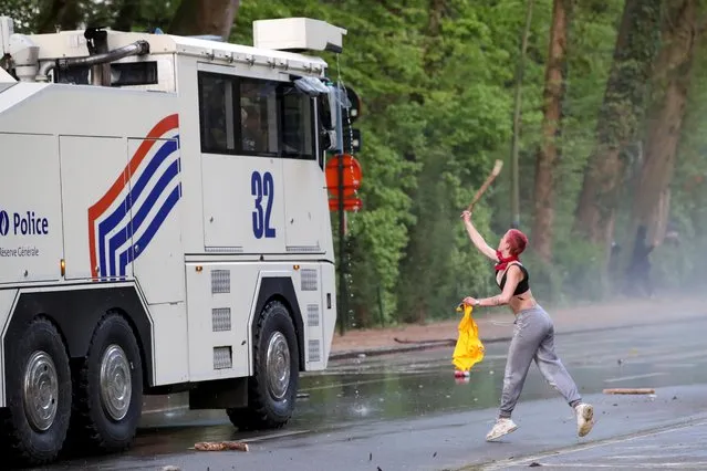A woman throws an object at police vehicle during clashes as people gather at the Bois de la Cambre/Ter Kamerenbos park for a party called “La Boum 2” in defiance of Belgium's coronavirus disease (COVID-19) social distancing measures and restrictions, in Brussels, Belgium on May 1, 2021. (Photo by Yves Herman/Reuters)