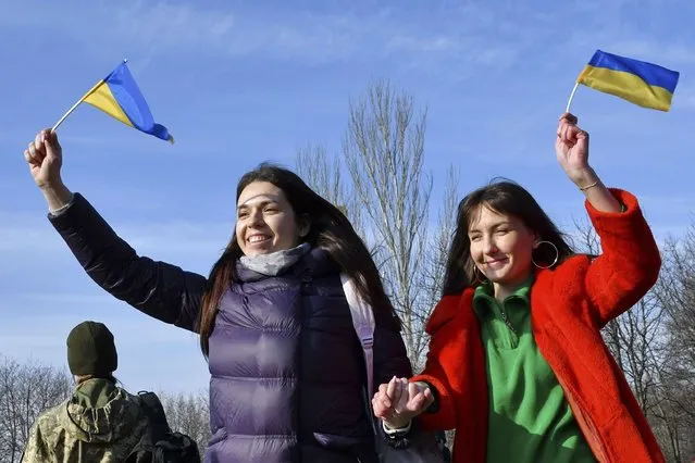 Two women wave Ukrainian national flags marking a Day of Unity in Kramatorsk, Ukraine, Wednesday, February 16, 2022.As Western officials warned a Russian invasion could happen as early as today, the Ukrainian President Zelenskyy called for a Day of Unity, with Ukrainians encouraged to raise Ukrainian flags across the country. (Photo by Andriy Andriyenko/AP Photo)