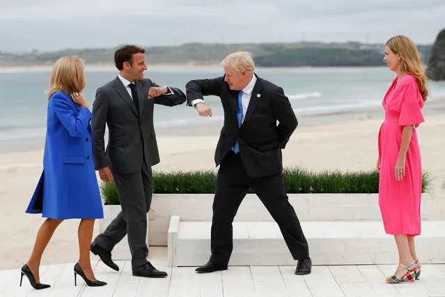 Britain's Prime Minister Boris Johnson (C,R) greets France's President Emmanuel Macron (C,L) as their spouses, Carrie Johnson (R) and Brigitte Macron, stand near during the G7 summit in Carbis Bay, Cornwall, on June 11, 2021. (Photo by Phil Noble/Pool via AFP Photo)