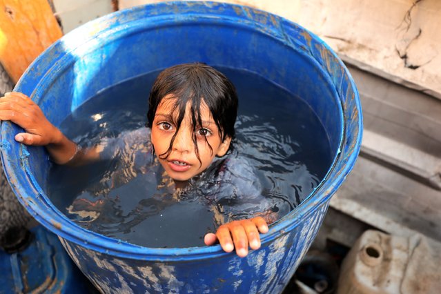 A Palestinian girl is seen inside the giant jerry can filled with water as displaced Palestinians, sheltering in tents they have set up in schools and along roadsides, experience the increasing temperatures in Deir al-Balah, Gaza, on June 11, 2024. Especially children are the most affected by the extremely hot weather conditions, while the number of Palestinians migrating to Deir al-Balah is increasing day by day due to Israeli attacks on different parts of Gaza. (Photo by Hasan Jedi/Anadolu via Getty Images)