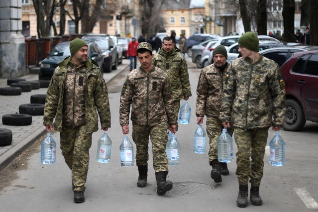 Ukrainian soldiers carry water supplies near a military base in Lviv on March 2, 2022. Russia steps up its bombing campaign and missile strikes on Ukraine's cities on March 2, 2022. (Photo by Daniel Leal/AFP Photo)