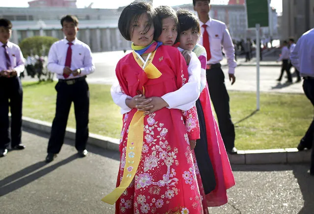 North Korean girls wearing traditional dresses, hug each other while waiting for their friends in front of Kim Il Sung Square on Wednesday, April 12, 2017, in Pyongyang, North Korea. North Korea will mark the 105th anniversary of the birth of late leader Kim Il Sung on April 15. (Photo by Wong Maye-E/AP Photo)