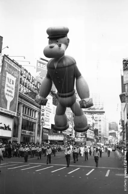 A giant inflatable Popeye floating over Times Square, New York, during a Thanksgiving Parade, 1961