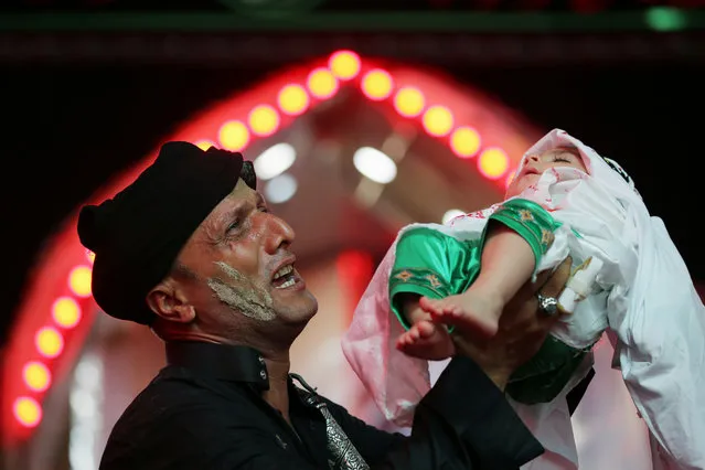 A Shi'ite Muslim holds a child as he takes part in an Ashura procession in the holy city of Kerbala, Iraq, September 9, 2019. (Photo by Abdullah Dhiaa Al-Deen/Reuters)