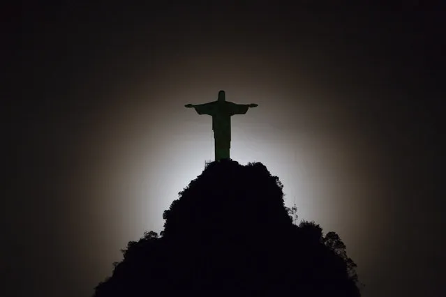 Christ the Redeemer statue is silhouetted against the glow of the moonset in Rio de Janeiro, Brazil, Tuesday, May 13, 2014.  As opening day for the World Cup approaches, people continue to stage protests, some about the billions of dollars spent on the World Cup at a time of social hardship, but soccer is still a unifying force. The international soccer tournament will be the first in the South American nation since 1950. (Photo by Felipe Dana/AP Photo)