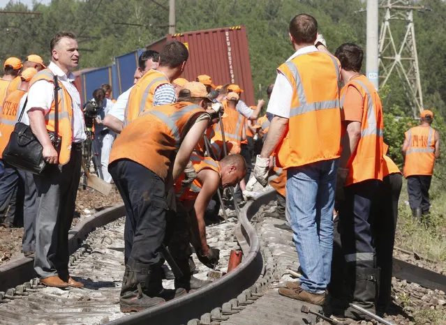 Employees of repair services work at the site of a train collision in Moscow region May 20, 2014. A passenger train on its way to Moldova collided with a freight train near Moscow on Tuesday, killing at least four people and injuring 15, a spokeswoman for Russia's Emergencies Ministry said. The reason for the collision, near the town of Naro-Fominsk 55 km (34 miles) southwest of Moscow, was not immediately clear. (Photo by Grigory Dukor/Reuters)