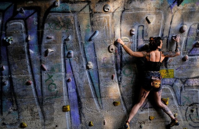 A woman climbs the walls of the Foixarda tunnel, a former road tunnel transformed into an urban, free-to-use climbing gym open at all times, equipped with thousands of holds, in Barcelona, Spain on June 29, 2024. (Photo by Nacho Doce/Reuters)