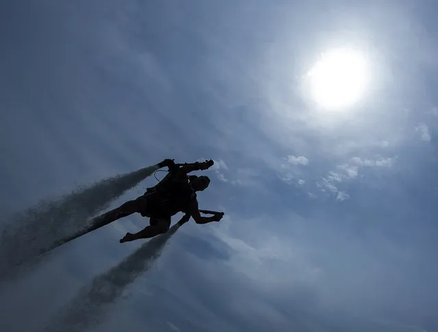 Andrew Scordilis uses a  a Jetlev Flyer during a performance for the press at the Stoermthaler Lake in Grosspoesna near Leipzig, Germany, Friday, July 17, 2015. (Photo by Jens Meyer/AP Photo)
