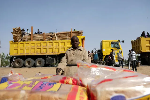 A refugee boy selling loaves of bread pushes his cart past trucks full of people in the Muna Garage Maiduguri, Nigeria February 16, 2017. (Photo by Paul Carsten/Reuters)