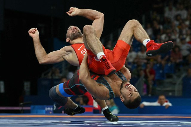 Serbia's Mate Nemes (red) wrestles Kyrgyzstan's Amantur Ismailov (blue) in their men's greco-roman 67kg wrestling repechage match at the Champ-de-Mars Arena during the Paris 2024 Olympic Games, in Paris on August 8, 2024. (Photo by Luis Robayo/AFP Photo)