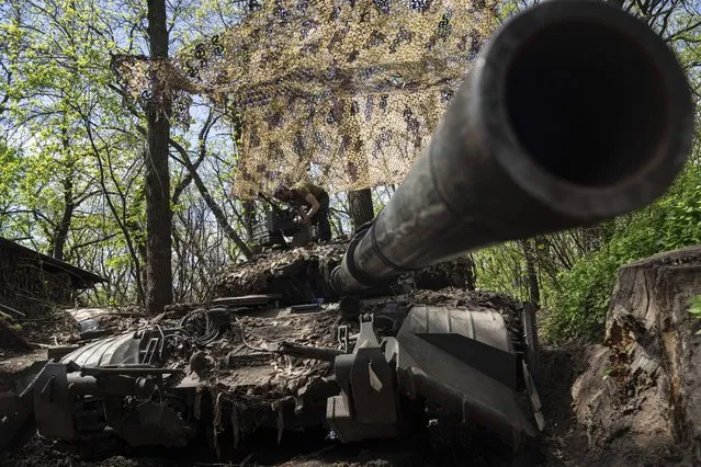 Ukrainian serviceman install a machine gun on the tank during the repair works after fighting against Russian forces in Donetsk region, eastern Ukraine, Wednesday, April 27, 2022. (Photo by Evgeniy Maloletka/AP Photo)