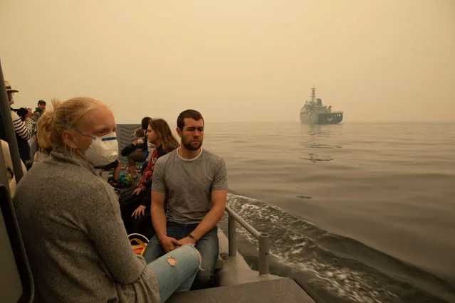 This handout photo taken on January 3, 2020 and released by the Royal Australian Navy shows people being evacuated from Mallacoota, Victoria state on a landing craft to MV Sycamore, during bushfire relief efforts. The Australian military on January 3 has begun the seaborne evacuation of hundreds of people trapped in a fire-ringed southeastern town, as the country braced for more catastrophic conditions. (Photo by Shane Cameron/Royal Australian Navy/AFP Photo)