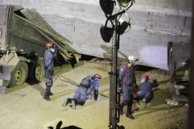 Fire department personnel look underneath a bridge that collapsed in Belo Horizonte, Brazil, Thursday, July 3, 2014. The overpass under construction collapsed Thursday in the Brazilian World Cup host city. The incident took place on a main avenue, the expansion of which was part of the World Cup infrastructure plan but, like most urban mobility projects related to the Cup, was not finished on time for the event. (Photo by Victor R. Caivano/AP Photo)