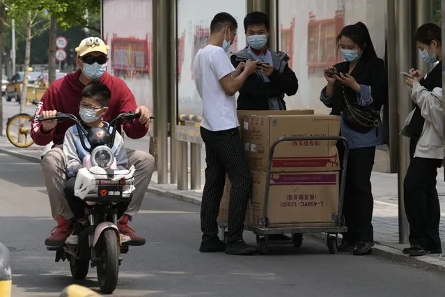 Residents wearing mask are seen on the street on Thursday, May 19, 2022, in Beijing. (Photo by Ng Han Guan/AP Photo)