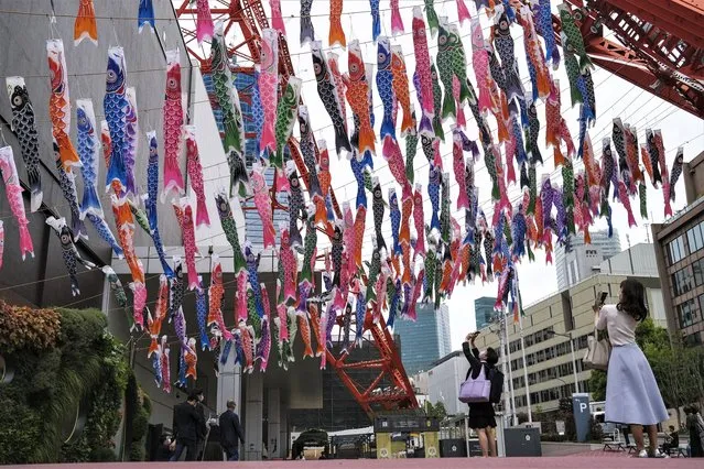 People take pictures of Koinobori, colorful carp streamers, on display at the base of Tokyo Tower Wednesday, April 27, 2022, in Tokyo. Koinobori are traditionally flown to celebrate Children's Day on May 5. (Photo by Kiichiro Sato/AP Photo)