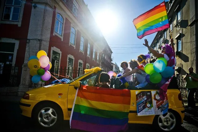 A car passes with people holding balloons and rainbow flags during the Gay Pride Parade in Lisbon on June 18, 2016. (Photo by Patricia De Melo Moreira/AFP Photo)