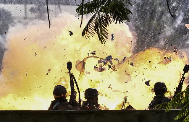 Members of the National Guard are caught up in a blast during protests in Caracas on July 10, 2017. Venezuela hit its 100th day of anti-government protests Sunday, amid uncertainty over whether the release from prison a day earlier of prominent political prisoner Leopoldo Lopez might open the way to negotiations to defuse the profound crisis gripping the country. (Photo by Carlos Becerra/AFP Photo)