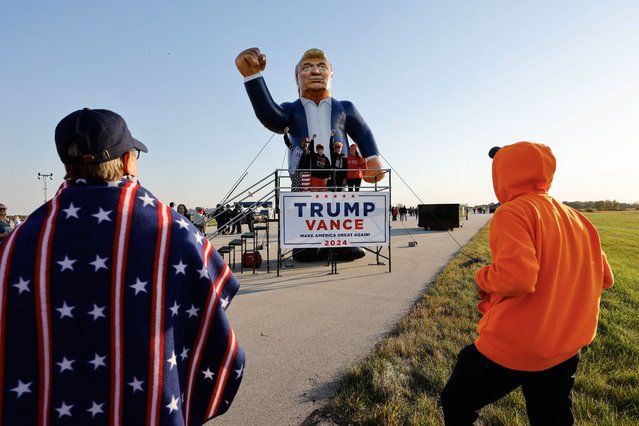 Supporters look at a large inflatable figure of former US President and Republican presidential nominee Donald Trump ahead of his campaign rally at the Dodge County Airport in Juneau, Wisconsin, USA, 06 October 2024. Donald Trump returns to the battleground state of Wisconsin for his fourth campaign event in less than ten days. (Photo by Jeffrey Phelps/EPA/EFE)