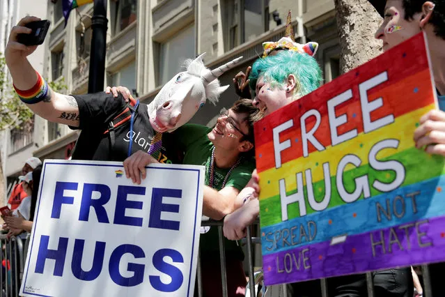 A man wearing a horse head mask takes a selfie with a man holding a “free hugs” sign at the San Francisco LGBT Pride Parade in San Francisco, California, U.S. June 26, 2016. (Photo by Elijah Nouvelage/Reuters)