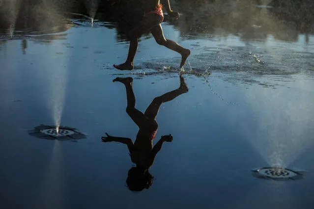 A picture made available on 09 July 2015 shows the reflection of a girl playing between the water jets of a fountain in Madrid's Rio area, in Madrid, Spain, 08 July 2015. (Photo by Emilio Naranjo/EPA)