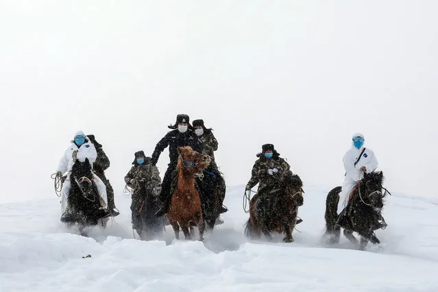 This photo taken on February 19, 2020 shows police officers wearing protective face masks riding horses on their way to visit residents who live in remote areas in Altay, farwest China's Xinjiang region, to promote the awareness of the virus. The death toll from China's new coronavirus epidemic jumped to 2,112 on February 20 after 108 more people died in Hubei province, the hard-hit epicentre of the outbreak. (Photo by AFP Photo/China Stringer Network)