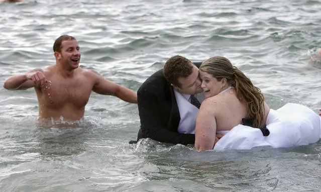Gerhard Pyper (C) kisses his new bride Jan in the waters of English Bay after taking part in the 89th annual Polar Bear Swim in Vancouver, British Columbia January 1, 2009. The couple celebrated their wedding the night before with a cold swim in the bay. (Photo by Andy Clark/Reuters)