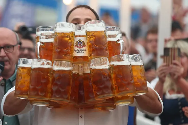 German Oliver Struempfel competes to set a new world record in carrying one liter beer mugs over a distance of 40 m (131 ft 3 in) in Abensberg, Germany September 3, 2017. Struempfel carried 27 mugs over 40 meters to set a new world record. (Photo by Michael Dalder/Reuters)