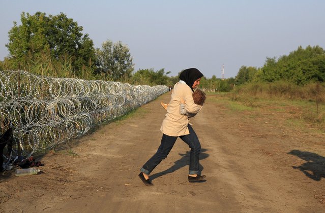 A Syrian migrant runs after crossing under a fence as she enters Hungary, at the border with Serbia, near Roszke, August 27, 2015. (Photo by Bernadett Szabo/Reuters)