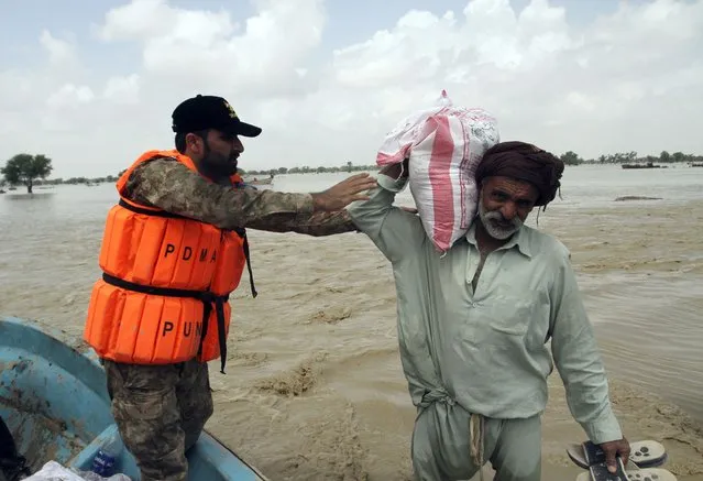 Pakistani man receive food, distribute by Pakistani Army troops in a flood-hit area in Rajanpur, district of Punjab, Pakistan, Saturday, August 27, 2022. Officials say flash floods triggered by heavy monsoon rains across much of Pakistan have killed nearly 1,000 people and displaced thousands more since mid-June. (Photo by Asim Tanveer/AP Photo)