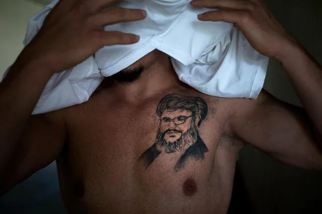 In this Tuesday, May 24, 2016 photo, Tayseer, 30, civil servant, covers his face as he poses for a photo showing a tattoo of Hezbollah leader Hassan Nasrallah, in the southern suburb of Beirut, Lebanon. He got it five months ago as an expression of “deep love” for the man he says is protecting Lebanon from Islamic State group and other extremists fighting in neighboring countries. (Photo by Hassan Ammar/AP Photo)