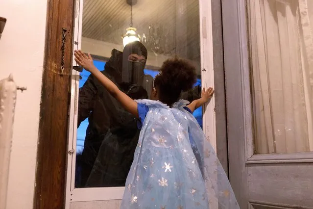 Hashim, an essential worker in the healthcare industry, speaks to his daughter through the closed door as he maintains social distance from his family as he works amid the outbreak in New Rochelle, New York, April 20, 2020. (Photo by Joy Malone/Reuters)