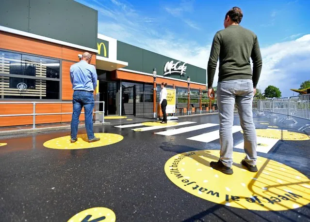 Customers wait outside on social distancing markings at a prototype location of fast food giant McDonald's for restaurants which respect the 1.5m social distancing measure, amid the coronavirus disease (COVID-19) outbreak, in Arnhem, Netherlands, May 1, 2020. (Photo by Piroschka van de Wouw/Reuters)