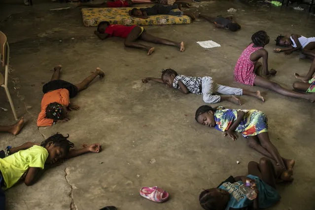 Children sleep on the floor of a school turned into a shelter after they were forced to leave their homes in Cite Soleil due to clashes between armed gangs, in Port-au-Prince, Haiti, Saturday, July 23, 2022. (Photo by Joseph Odelyn/AP Photo)